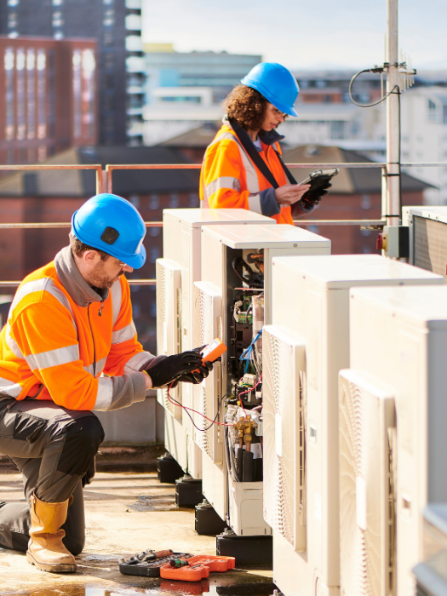 Two technicians are performing tests on external air cooling units.
