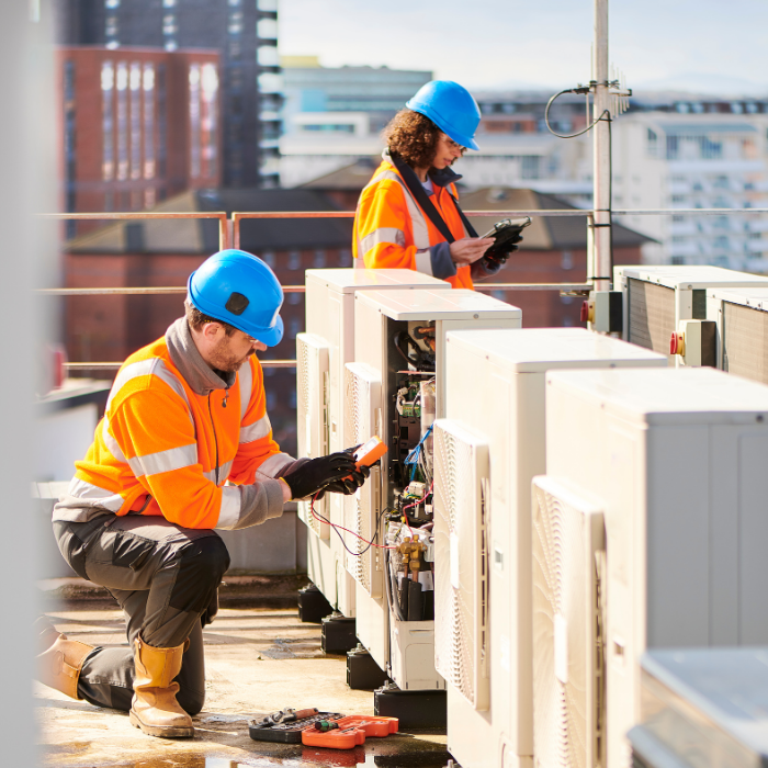 Two technicians are performing tests on external air cooling units.