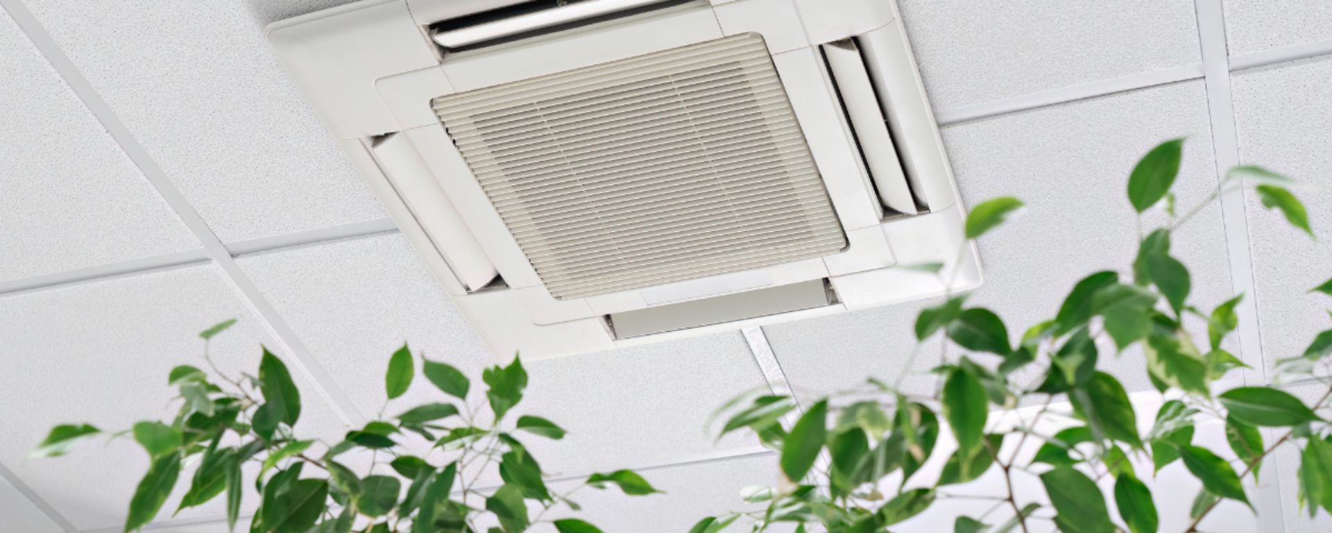 An air conditioning unit is installed flush to the ceiling, with a central grate and side flaps for directed cool air.