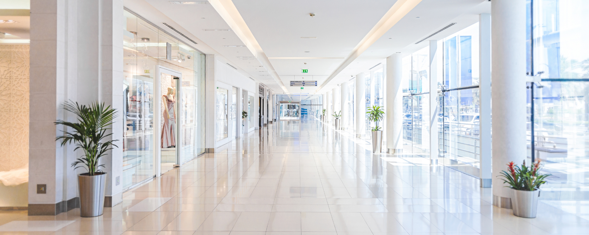 A modern indoor shopping centre with a glass front on the right, and a row of shops on the left.