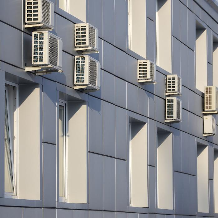 Several air cooling units are installed to the outside wall of a building.