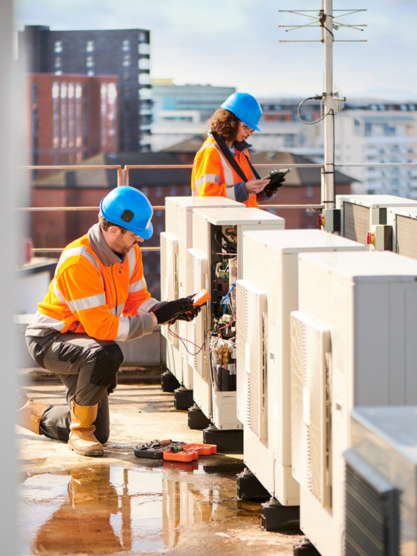Two technicians are performing tests on external air cooling units.