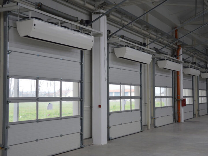 Fan curtains blow a stream of air over a large garage door opening.